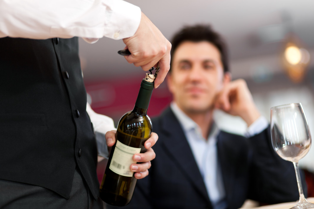 Waiter serving wine to a customer