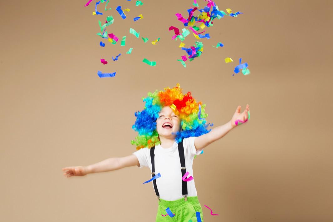 Happy clown boy in large colorful wig. Let's party! Funny kid clown. 1 April Fool's day concept.