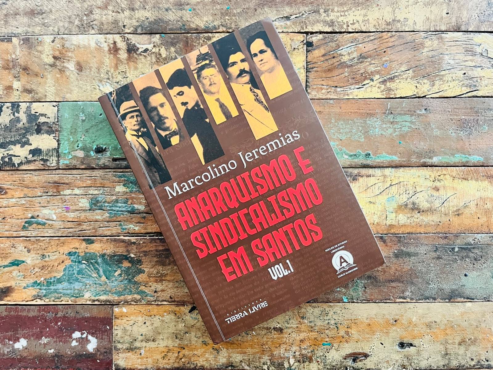 Livro 'Anarquismo e Sindicalismo em Santos Vol.1' de Marcolino Jeremias em capa marrom com fotos antigas sobre madeira rústica.
