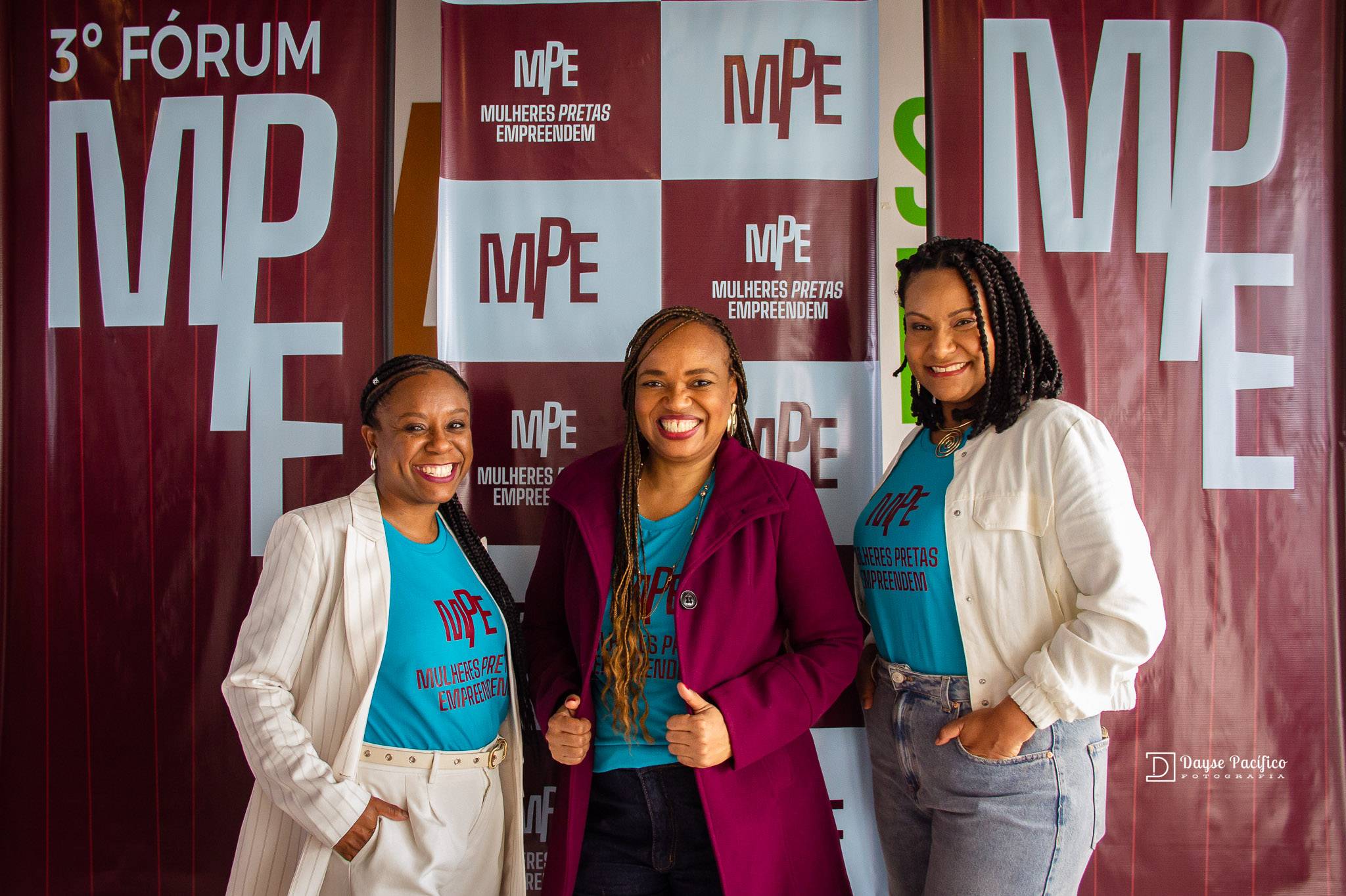 Três mulheres negras sorridentes, usando camisetas do MPE, posam para foto no 3º Fórum Mulheres Pretas Empreendem.